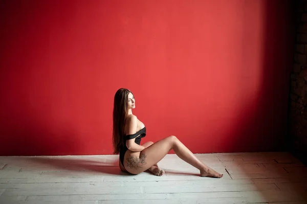 Retrato Uma Mulher Tatuada Vestindo Bodysuit Preto Sentado Chão Estúdio — Fotografia de Stock