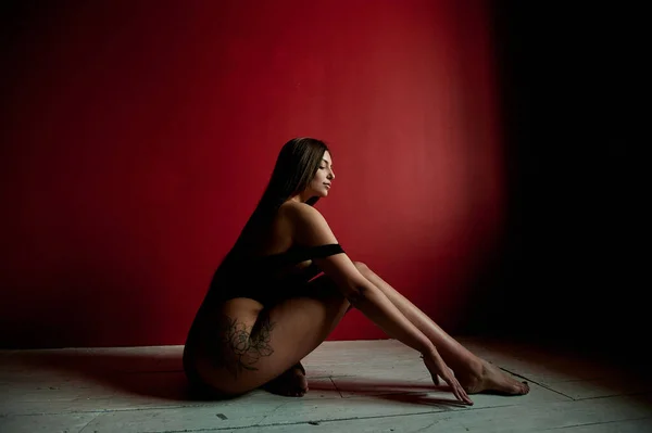 Retrato Uma Mulher Tatuada Vestindo Bodysuit Preto Sentado Chão Estúdio — Fotografia de Stock