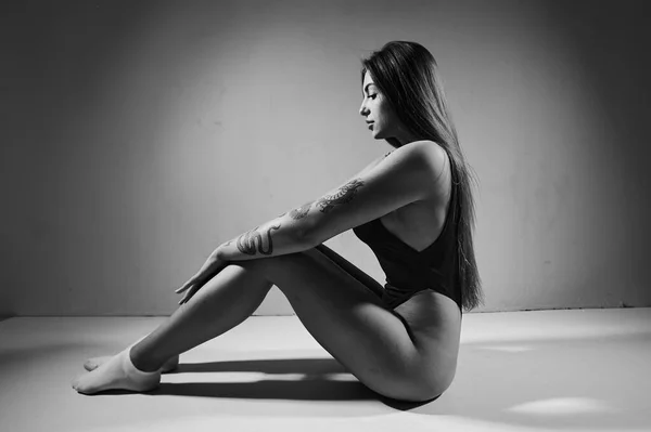 Портрет Женщины Татуировкой Чёрном Боди Костюме Сидящей Полу Студии Концепция — стоковое фото