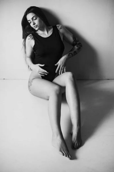 Retrato Uma Mulher Tatuada Vestindo Bodysuit Preto Sentado Chão Estúdio — Fotografia de Stock