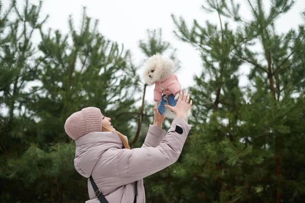 Outdoor travel with dog. Happy moments with pets.  Woman holds happy pet dog pomeranian spitz. Silver bracelet on hand. Spending time with lovely white fluffy puppy.