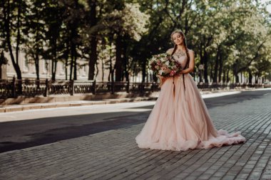 İki örgülü, güzel, uzun saçlı bir gelinin portresi. Elinde koca bir buket düğün çiçeği olan bir kız. Dövmeli kadın çok güzel pembe bir gelinlik giymiş..