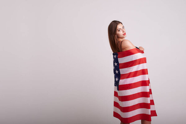 Beautiful sport woman holding american flag and smiling