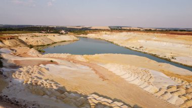 Kum ocağı. Turkuaz lagün ve yüzey mayınları açıkta kalmış renkli mineraller, çukurun dibinde ekipmanlar..