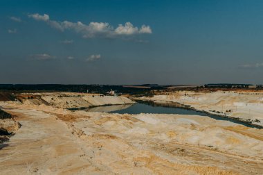 Kum ocağı. Turkuaz lagün ve yüzey mayınları açıkta kalmış renkli mineraller, çukurun dibinde ekipmanlar..