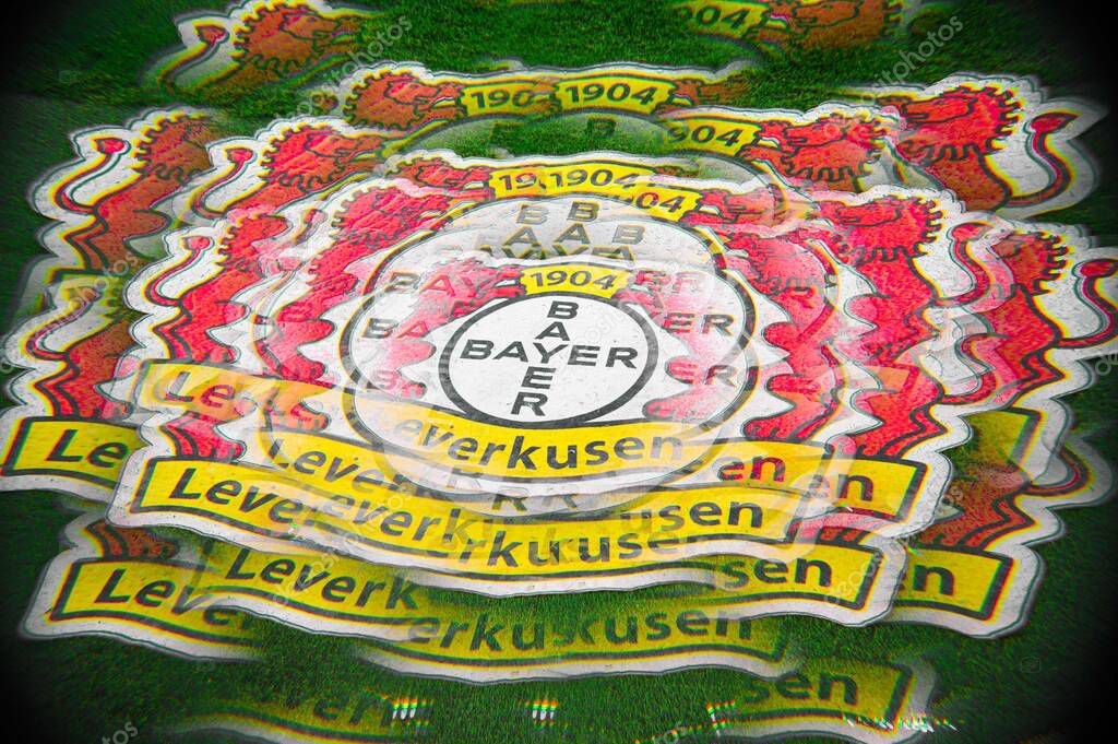 LEVERKUSEN, GERMANY - 17 DECEMBER, 2023: Wide multi-exposure of the Bayer 04 Leverkusen crest on green turf, repeated layers creating vibrant motion effect. Graphic stadium detail at BayArena.