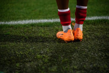 COLOGNE, ALMANY - 16 EKİM, 2025: yakın plan parlak turuncu Puma ULTRA futbol botları dokunuş çizgisinin yanındaki ıslak çimlerde. Başlangıç öncesi ekipman detayı. 1.FC Koeln Frauen, FRANZ-KREMER STADION 'da Bayer 04 Frauen' e karşı