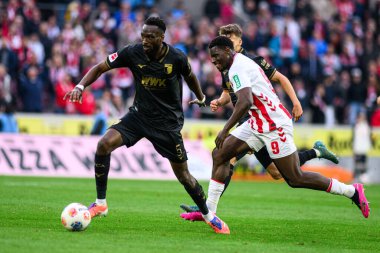 COLOGNE, GERMANY - 18 Ekim 2025: Chrikilled Matsima, Ragnar Ache - Bundesliga 1 'in futbol maçı. FC Koeln, FC Augsburg 'a karşı Rhein Enerji Stadyumu' nda.