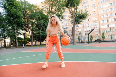 Kendine güvenen bayan oyuncu topu yakın mesafeden sürüyor, çapraz atışa hazır. Sokak sporu enerjisi.