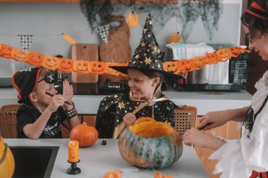 Bir anne, oğul ve kız Cadılar Bayramı balkabaklarını dekore edilmiş mutfakta oyuyorlar. Çocuklar oynuyorlar ve birbirlerini korkutuyorlar. Kız cadı gibi giyinmiş, erkek kardeşi de korsan gibi giyinmiş..