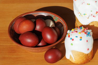 Geleneksel Paskalya kırmızı yumurtaları kil bir kasede, ahşap masa üzerinde şenlikli pasta, sade ve fotokopi alanı olan..