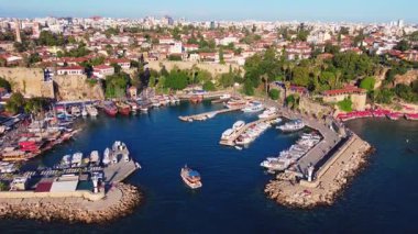 İHA, Antalyas Eski Şehir Limanı 'nın panoramik manzarasını gözler önüne sermek için iniyor. Gündüz vakti tarihi duvarlar, botlar, rıhtımlar ve canlı Akdeniz sahili manzarasını gösteriyor..