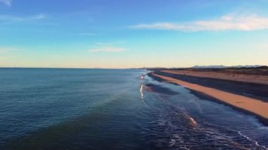 Gün batımında Valencia 'daki El Saler plajı boyunca hava aracı uçuşu. Kumlu kumulların üzerinde altın ışık, sakin Akdeniz ve boş kıyı şeridi.