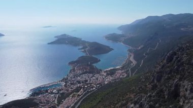 Kızıl çatıları, dolambaçlı yolu, turkuaz Akdeniz ve çevresindeki dağlarla Kas şehrinin hava panoramik manzarası. Notlandırılmamış, Dlog