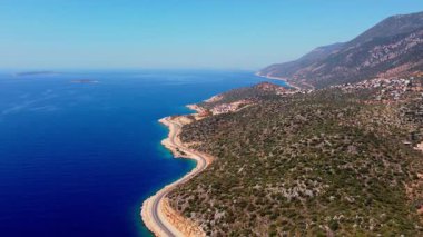 Kas yakınlarındaki hava panoramik manzarasında dolambaçlı bir kıyı yolu, engebeli dağlar ve derin mavi Akdeniz yer alıyor. Manzaralı seyahat görüntüleri, özgürlük ve yolculuk konsepti.