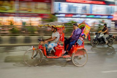 Geceleri renkli renkli bir triportörün hareket bulanıklığı. Renkli, süslü bir elektrikli triportör gece şehir trafiğinde hareket ediyor. Bu resim Güney Asya 'da bulunan eşsiz halk sanatını ve geleneksel ulaşımı yansıtıyor..