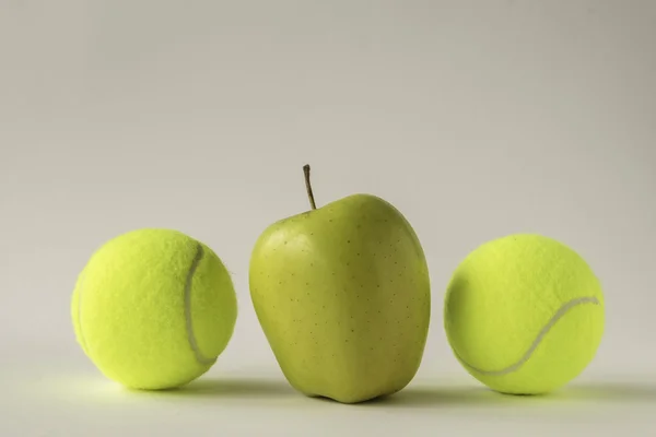 Maçã amarela entre duas bolas de tênis Fotos De Bancos De Imagens