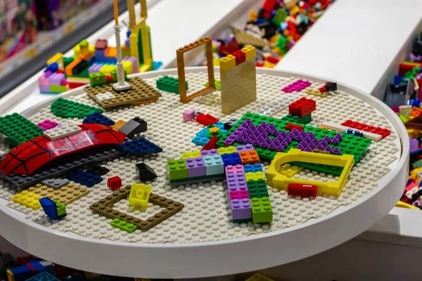 Parlak LEGO tuğlaları ve renkli parçalar yuvarlak beyaz bir masayı kaplayarak, çocuklar, aileler ve sınıf tasarım bağlamlarında hayal gücü ve hobileri ateşleyen eğlenceli, yaratıcı bir sahne yaratıyor..