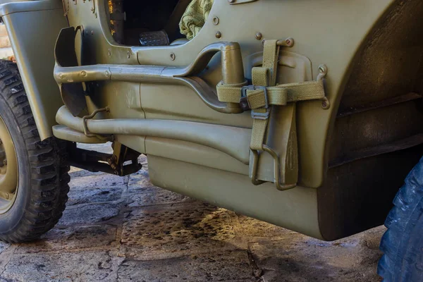 Olive Drab Askeri Jeep 'in kayışlı, aletli ve çamur korumalı yakın çekimi.