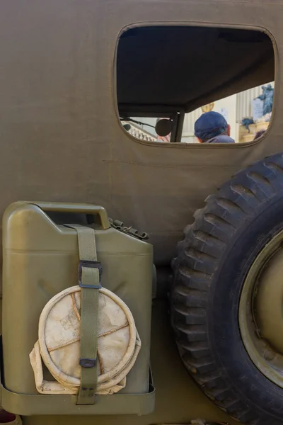 Çadır bezi kaplamalı askeri cip, Jerry Can, ve arkada geniş yedek lastik, açık hava dişlisi.