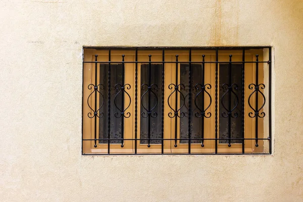 Dekoratif Demir Pencere Parmaklıklı Sarı Duvar Sessiz bir Sokak Sahnesinde Bej bir cepheyi koruyor