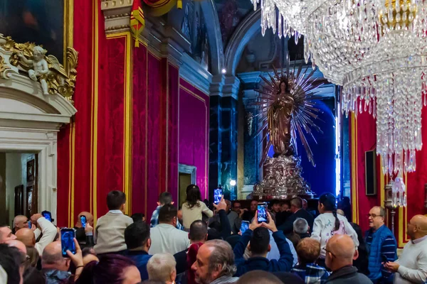 Cospicua, Malta - November 28th, 2025, Crowded Church Interior With Ornate Altar Statue And Crystal Chandeliers During Ceremony