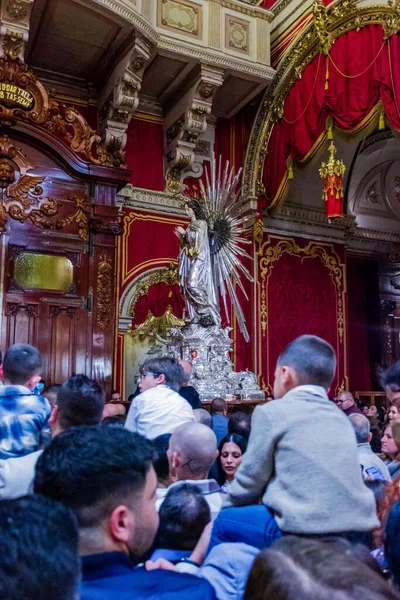 Cospicua, Malta - November 28th, 2025, Crowded Church Interior With Silver Statues and Ornate Gold Altar During Religious Ceremony In Historic Cathedral