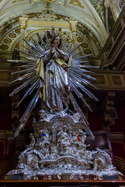 Cospicua, Malta - November 28th, 2025, Elegant Silver Angel Statue With Radiant Halo In Ornate Church Interior During Service