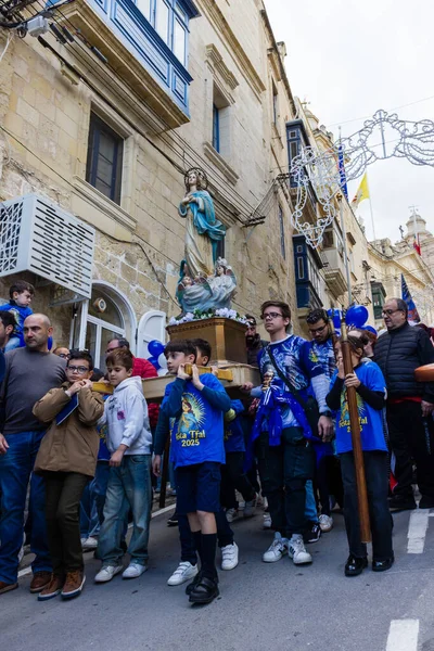 Cospicua, Malta - November 30th, 2025, Religious Festival Procession With Virgin Mary Statue Amid Crowded Street Parade During Festive Celebration