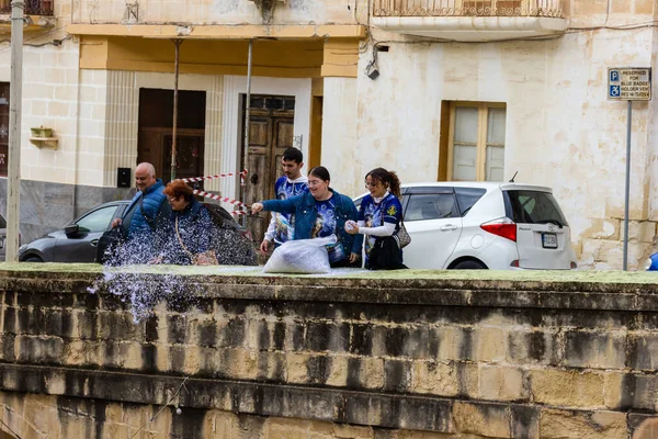 Cospicua, Malta - November 30th, 2025, Group Of Friends Splashing Water By Historic Waterfront Wall In Sunny Town During Warm Day