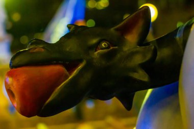 Siyah ejderha maskotunun gece vakti renkli ışıklarla çekilmiş yakın çekimi.