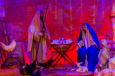 Meryem, Yusuf ve Bebek İsa ile Kırmızı ve Mavi Aydınlatma Altında Bir Ahırda Doğuş Sahnesi