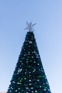 Büyük açık hava Noel Ağacı, tarihi binaların önündeki süslerle ve kar taneleriyle süslenir.