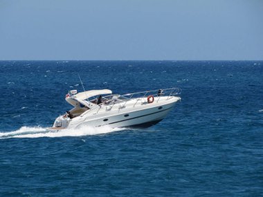 Beyaz Motorlu Tekne Mavi Okyanusu aşıyor Güneşli bir günde, Aile Hız Teknesi Yolculuğunun keyfini çıkarıyor