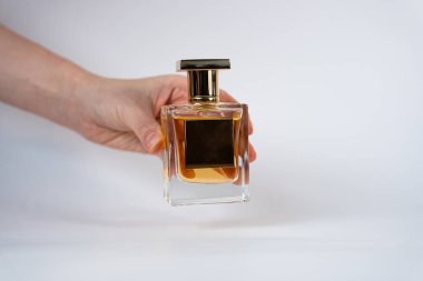 Close-up of a female hand holding a square perfume bottle with golden liquid. Perfect for perfume branding, beauty campaigns, fashion advertising, and luxury product design. 