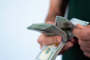 Close-up of two people exchanging dollar bills, symbol of partnership, trade, or financial agreement. 