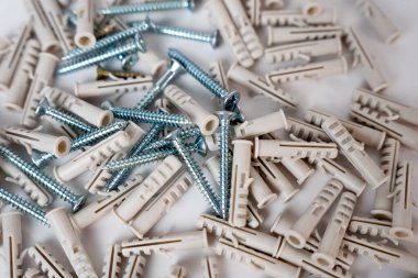 Close-up of a pile of metallic screws and plastic wall plugs. Great for hardware, building, or DIY concepts. 