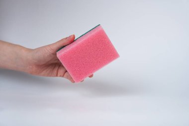 Hand holding pink cleaning sponge on white background. Household cleaning or hygiene concept, minimal style product photo. 