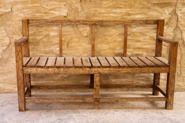 Geleneksel el yapımı ahşap bank Dubai miras bölgesinde eski bir kumtaşı duvarın yanında..