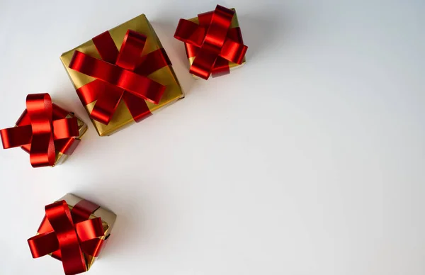 Beyaz arka planda altın kurdeleli küçük kırmızı hediye kutularının minimum üst görünümü, festival pazarlama ve reklamcılık için temiz kompozisyon. 
