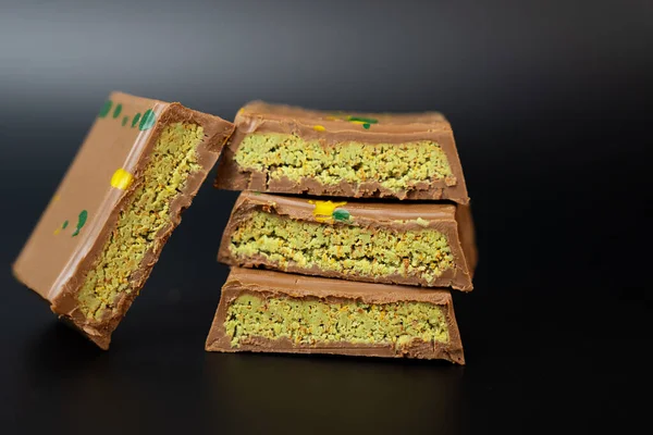 Şam fıstıklı çikolatalı karelerin sanatsal makro çekimi. Gurme ve lüks markalaşma için siyah, zengin yemek fotoğrafçılığı üzerine düzenlenmiş.. 