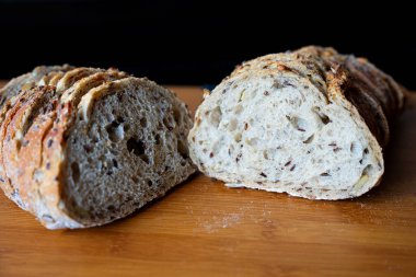 Tahtada ikiye bölünmüş taze pişmiş zanaatkar ekşi ekmek. Doğal ışıklandırma, yakın çekim kabuk ve kırıntı dokusu. Fırın, ev yapımı yemek ya da kırsal mutfak teması için mükemmel.. 