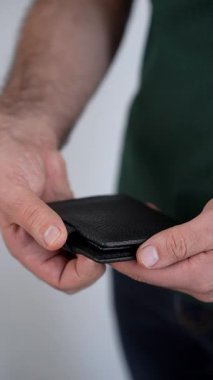 Erkek ellerinin siyah bir cüzdanı açıp 100 dolarlık banknotu çıkardığı yavaş çekim. Zenginlik, tasarruf, iş başarısı ve mali bağımsızlık kavramı. 