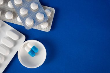 Mavi arka planda haplar, şişeler ve termometreyle yatıyordu. İlaç reklamları ve sağlık blogları için mükemmel..