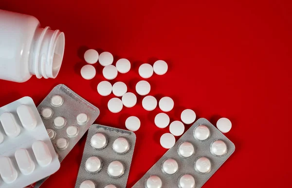 İlaç şişesi, su toplayan paketler ve canlı kırmızı tabletler, güvenlik, tedarik ve sağlık konuları için editoryal eczane imajı. Yüksek kalite fotoğraf