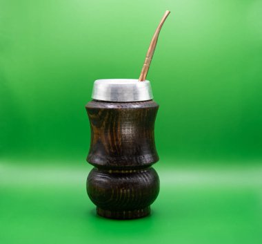Canlı yeşil arka planda metal bombilla ile siyah ahşap yerba mat kabağı. Güney Amerika bitki çayı kavramı enerjiyi, geleneği ve doğal yaşam tarzını sembolize eder.. 