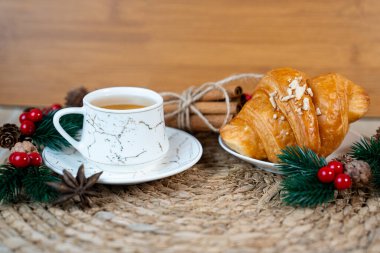Flaky croissants ve bir fincan çay sade örülmüş şenlikli paspasın üzerinde. Sıcak sıcak kahvaltı konsepti.. 