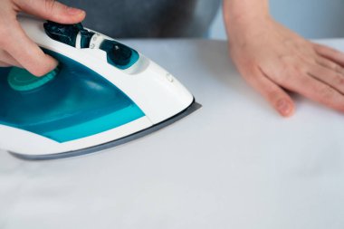 Beyaz bir kumaşı buhar ütüsüyle ütüleyen birinin yakın çekimi. Temiz ev işleri ve çamaşır konsepti. 