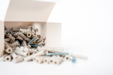 Beyaz arka plandaki açık bir kutudan yayılmış çeşitli vidalar ve duvar prizleri. İnşaat malzemeleri ve ev yenileme konsepti. Yüksek kalite fotoğraf