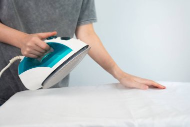  Ütü yapmadan önce kumaşı düzelten kişi. Temiz ve basit ev bakımı ve çamaşır konsepti. 